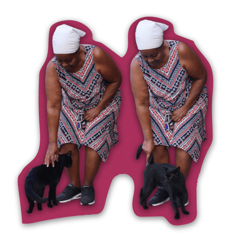 Mary Kennedy bends down to pet two black cats.